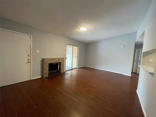 a view of empty room with wooden floor and fireplace