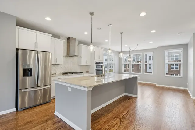 a kitchen with stainless steel appliances granite countertop a refrigerator a stove a sink and a wooden floors