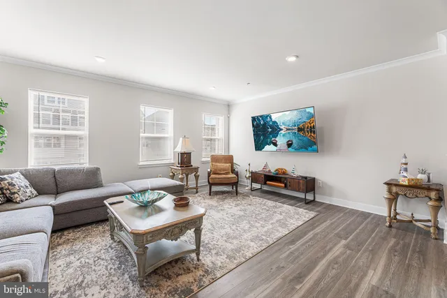 a kitchen with stainless steel appliances granite countertop a refrigerator a sink a stove a dining table and chairs with wooden floor