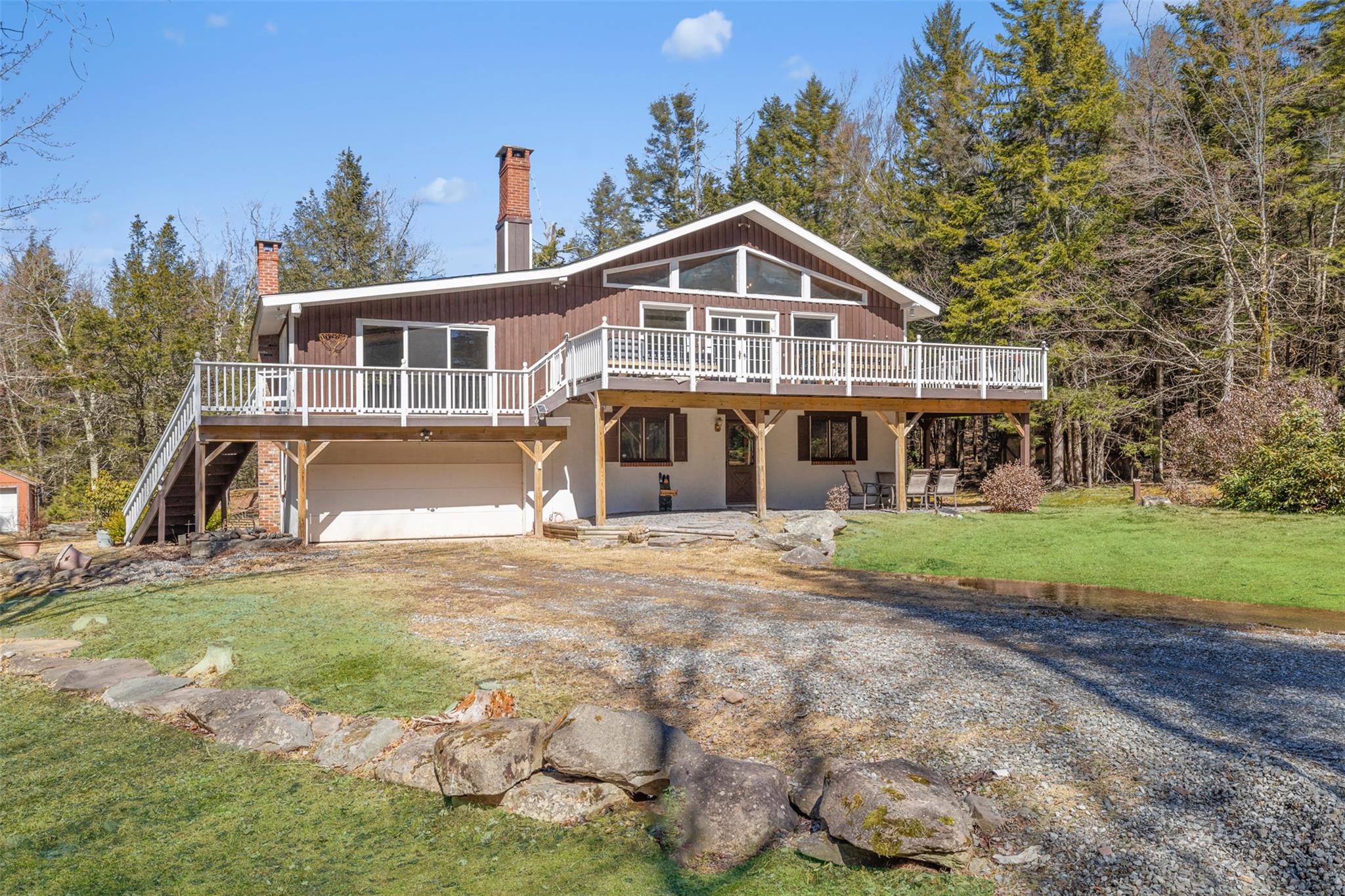 Back of house with dirt driveway, a chimney, a garage, board and batten siding, and a yard