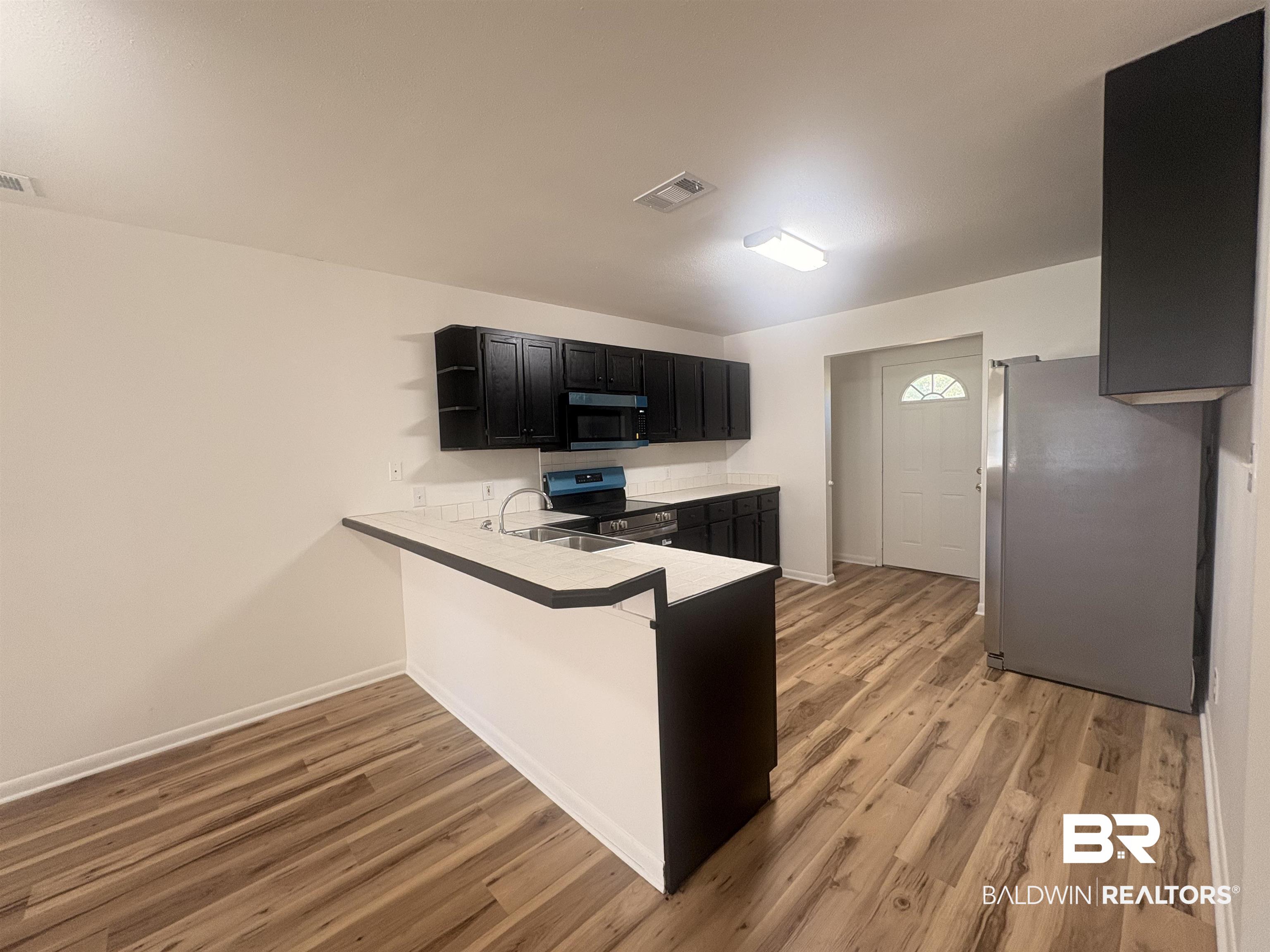 109-111 North Beech Street, Unit A & B Foley, AL 36535 - Photo 4 of 16 Kitchen featuring dark cabinets, appliances with stainless steel finishes, a peninsula, light countertops, and light wood finished floors