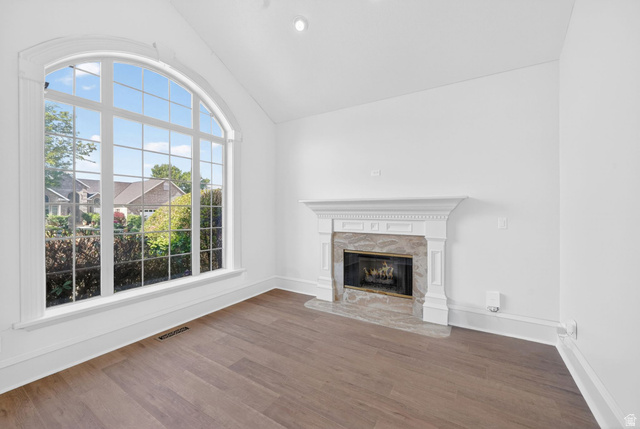 883 East 700 South Springville, UT 84663 - Photo 7 of 59 Arched picture window with gridded panes, high vaulted ceiling, wood-finish flooring, and a fireplace featuring a decorative mantel and stone surround