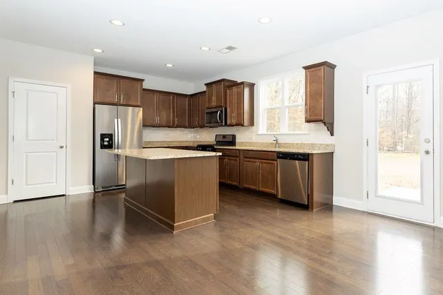 a kitchen with stainless steel appliances granite countertop a sink a stove and a refrigerator