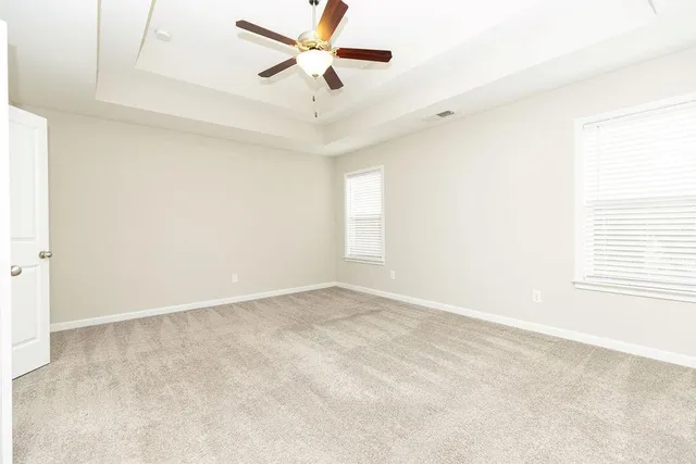 an empty room with windows and fan