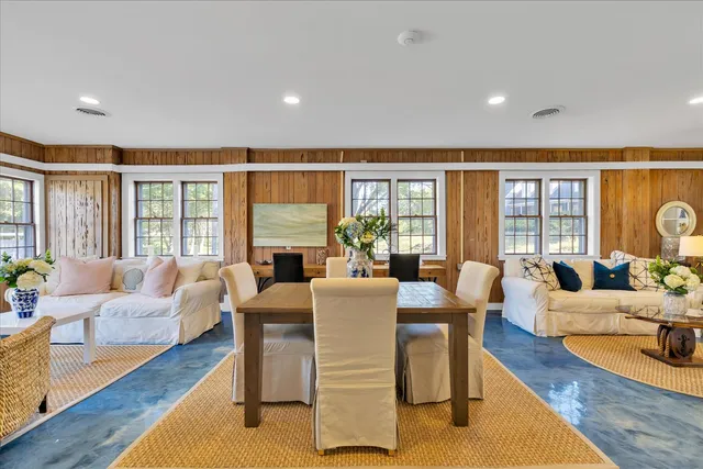 a living room with furniture large windows and wooden floor