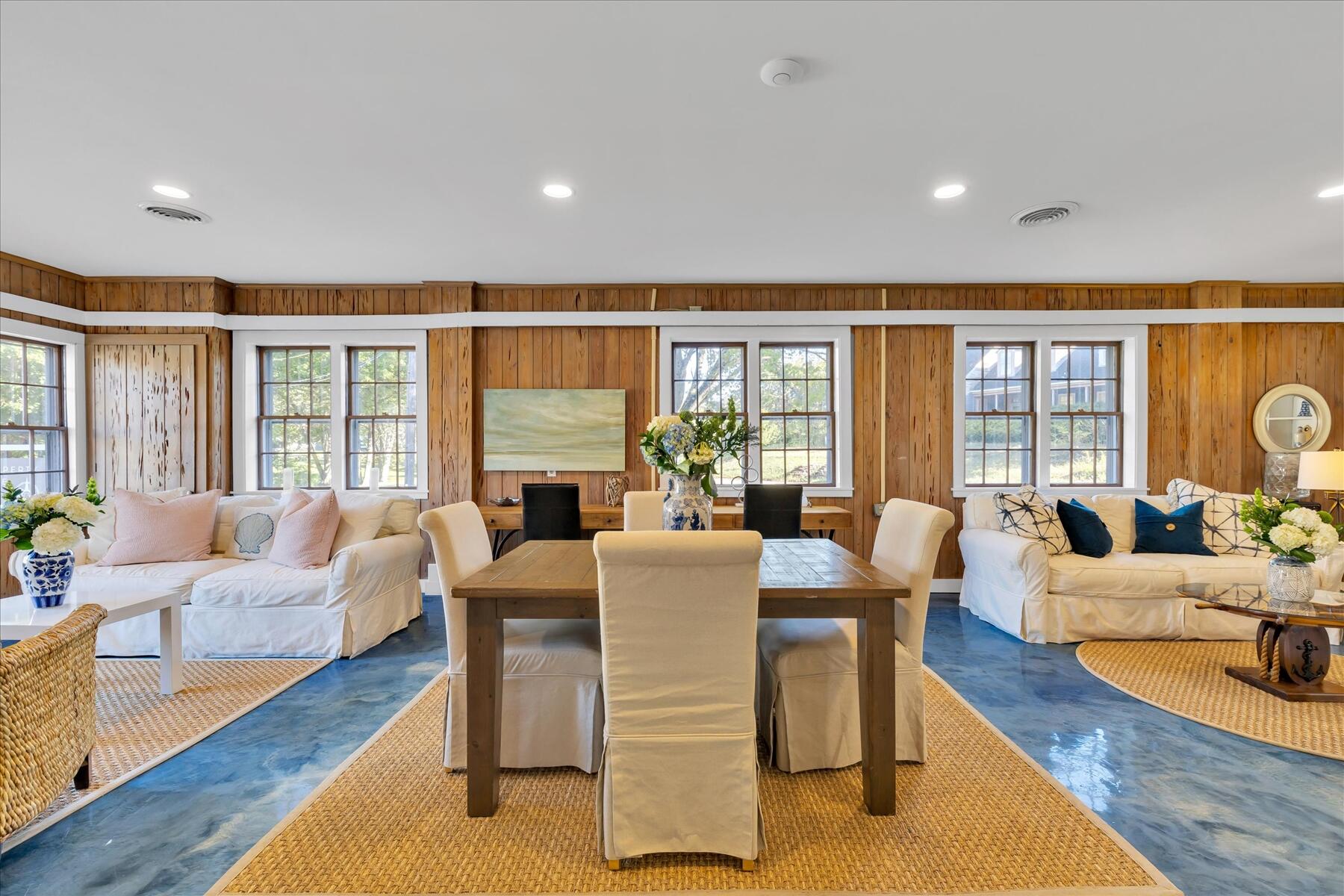 a living room with furniture large windows and wooden floor