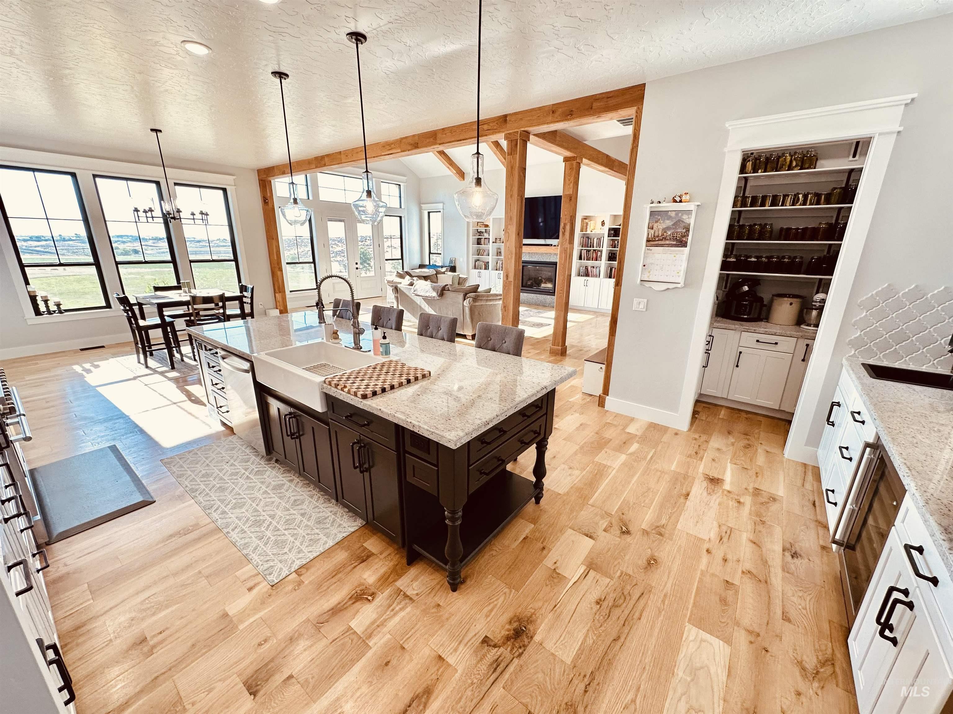 876 Coyote Gulch Road Adrian, OR 97901 - Photo 12 of 50 Open-concept kitchen featuring an oversized island with a farmhouse sink, light wood-finish flooring, and white cabinetry