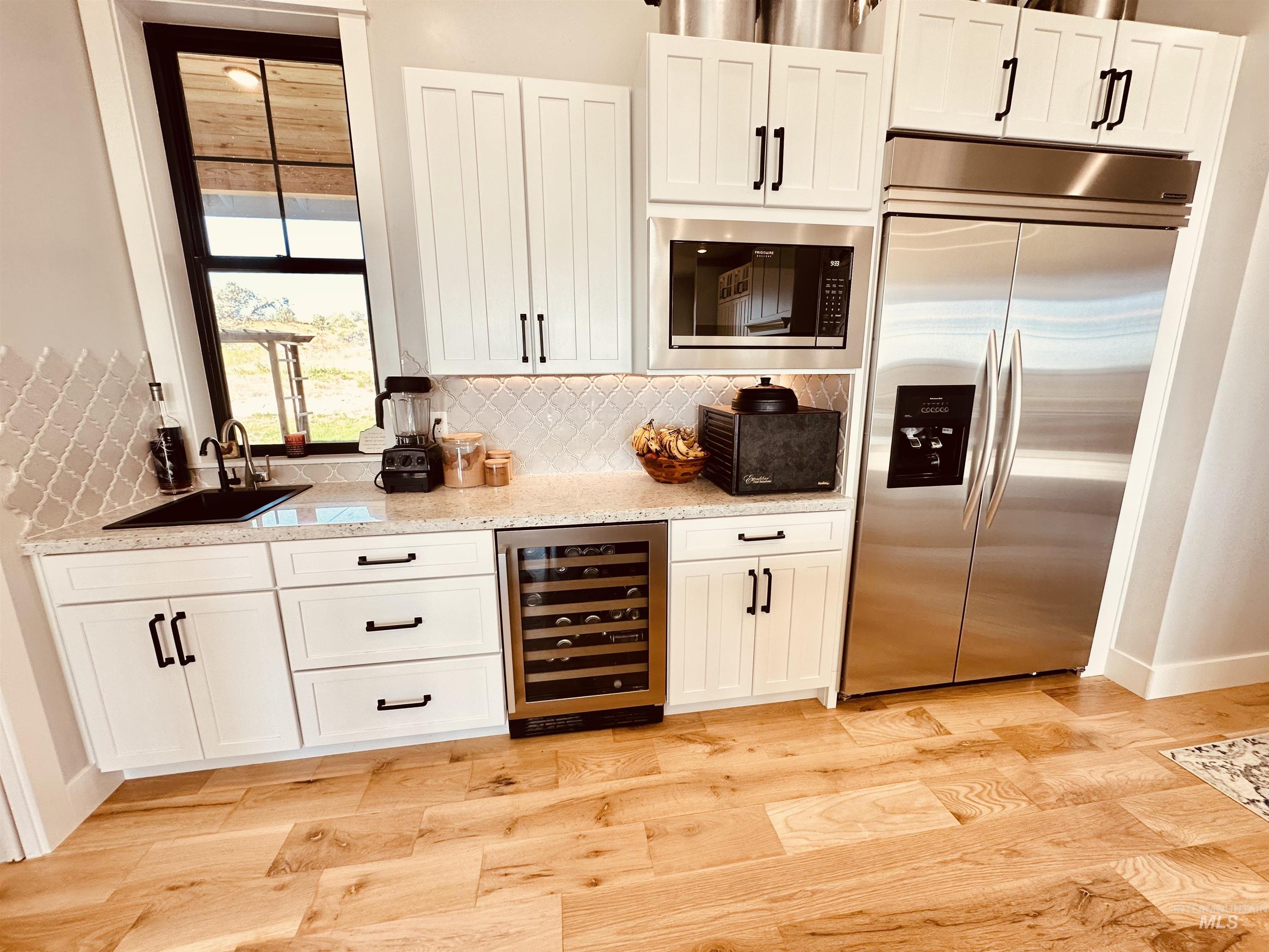 876 Coyote Gulch Road Adrian, OR 97901 - Photo 13 of 50 Kitchen featuring crisp white cabinetry, light speckled countertops, and a white arabesque tile backsplash