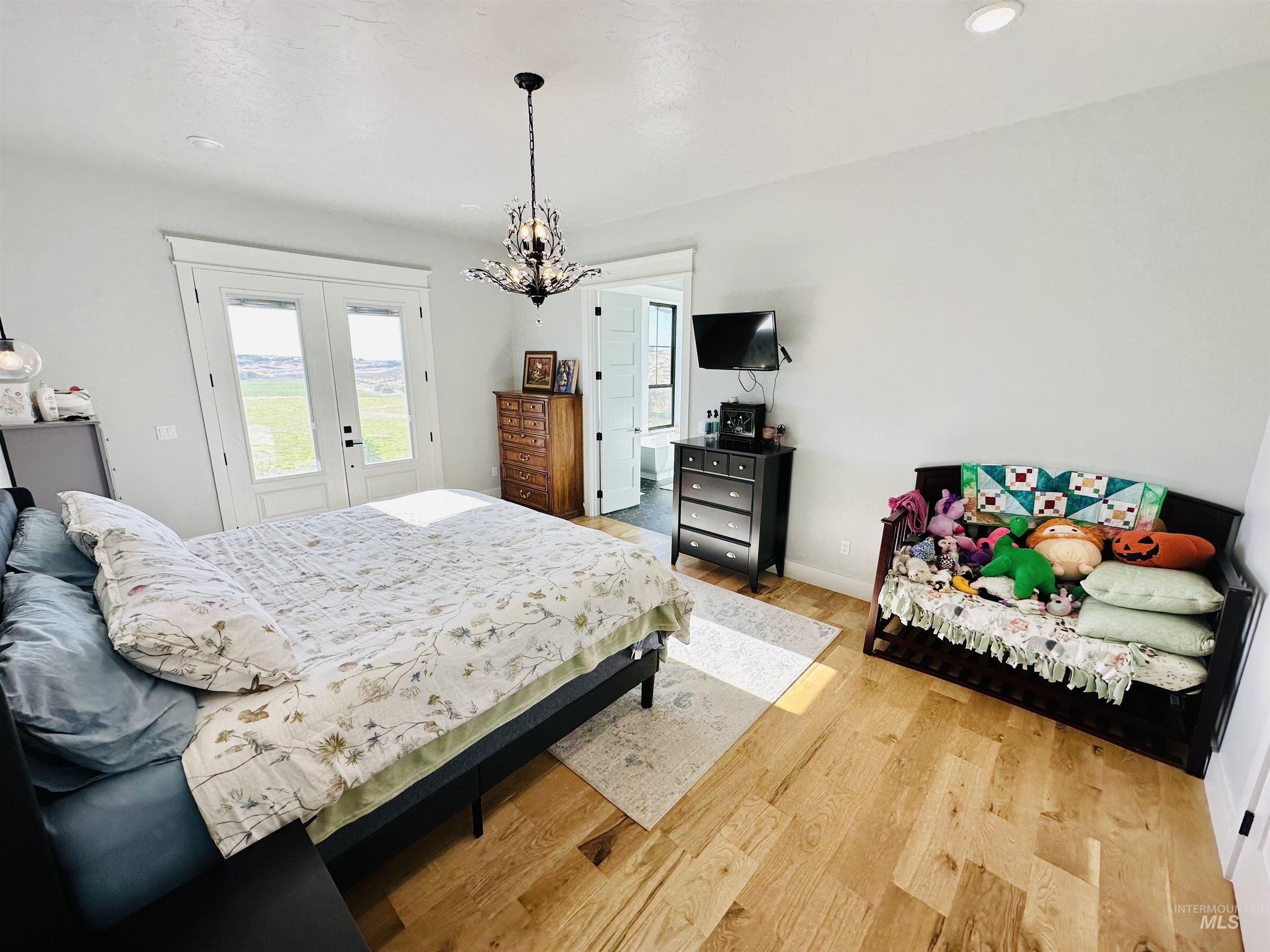 876 Coyote Gulch Road Adrian, OR 97901 - Photo 18 of 50 Spacious room featuring light wood-finish flooring, white walls, and a decorative chandelier