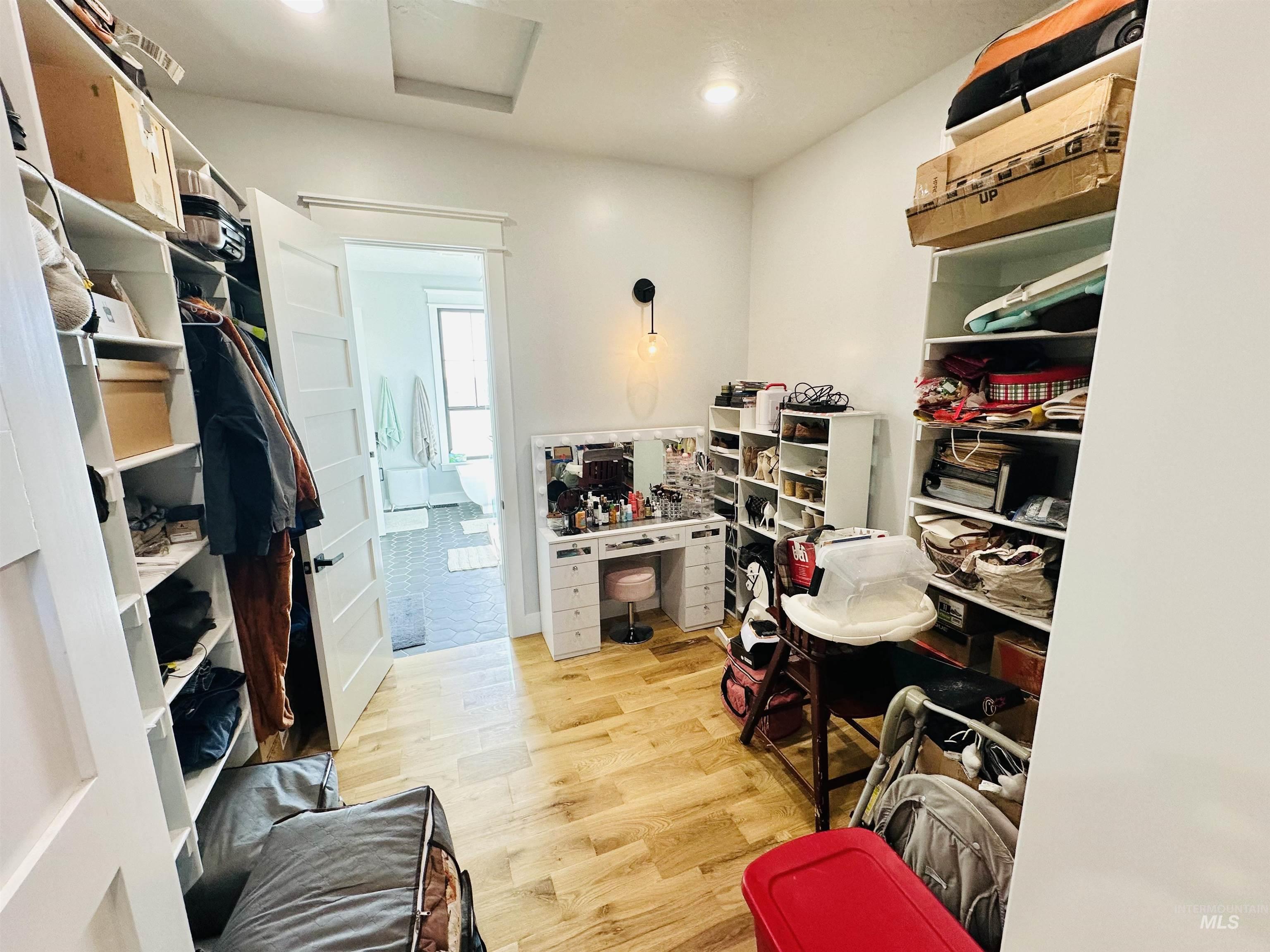 876 Coyote Gulch Road Adrian, OR 97901 - Photo 21 of 50 White-painted closet featuring built-in shelving, wood-finish flooring, and a doorway leading to a tiled bathroom