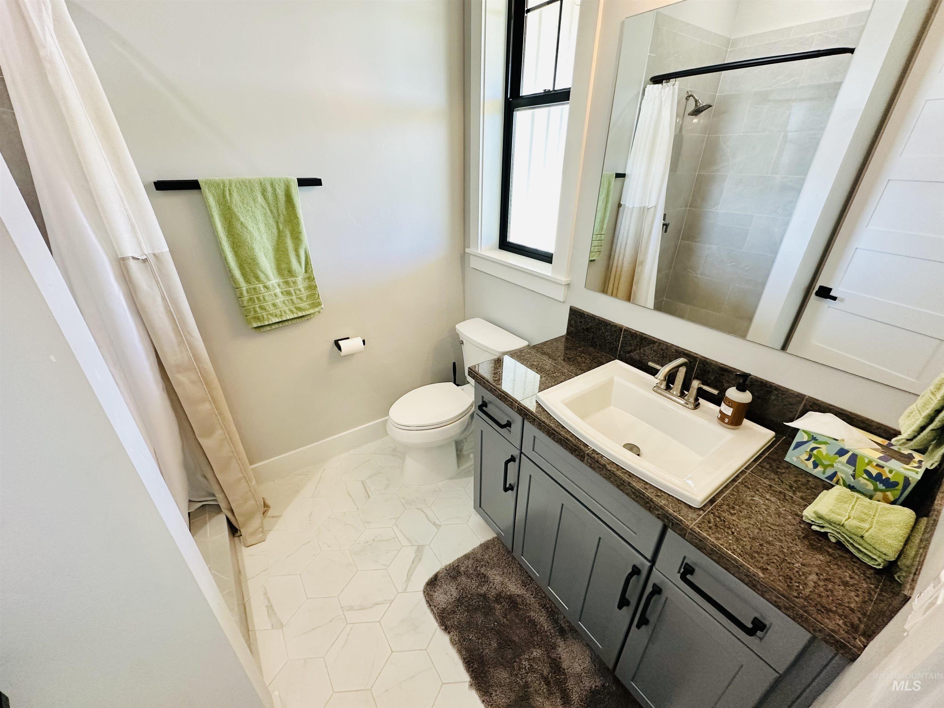 876 Coyote Gulch Road Adrian, OR 97901 - Photo 30 of 50 Bathroom featuring a vanity with a dark countertop and undermount sink, hexagonal floor tiling, and a black-framed window