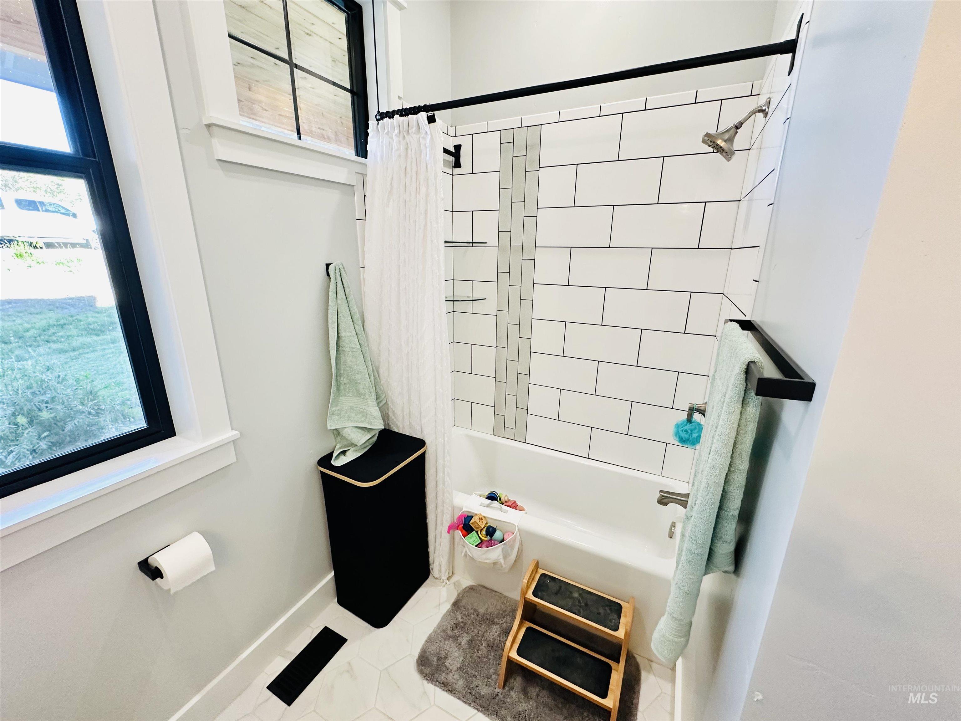 876 Coyote Gulch Road Adrian, OR 97901 - Photo 31 of 50 Contemporary bathroom featuring a subway tile shower surround with a vertical accent tile stripe, a white bathtub, and matte black hardware
