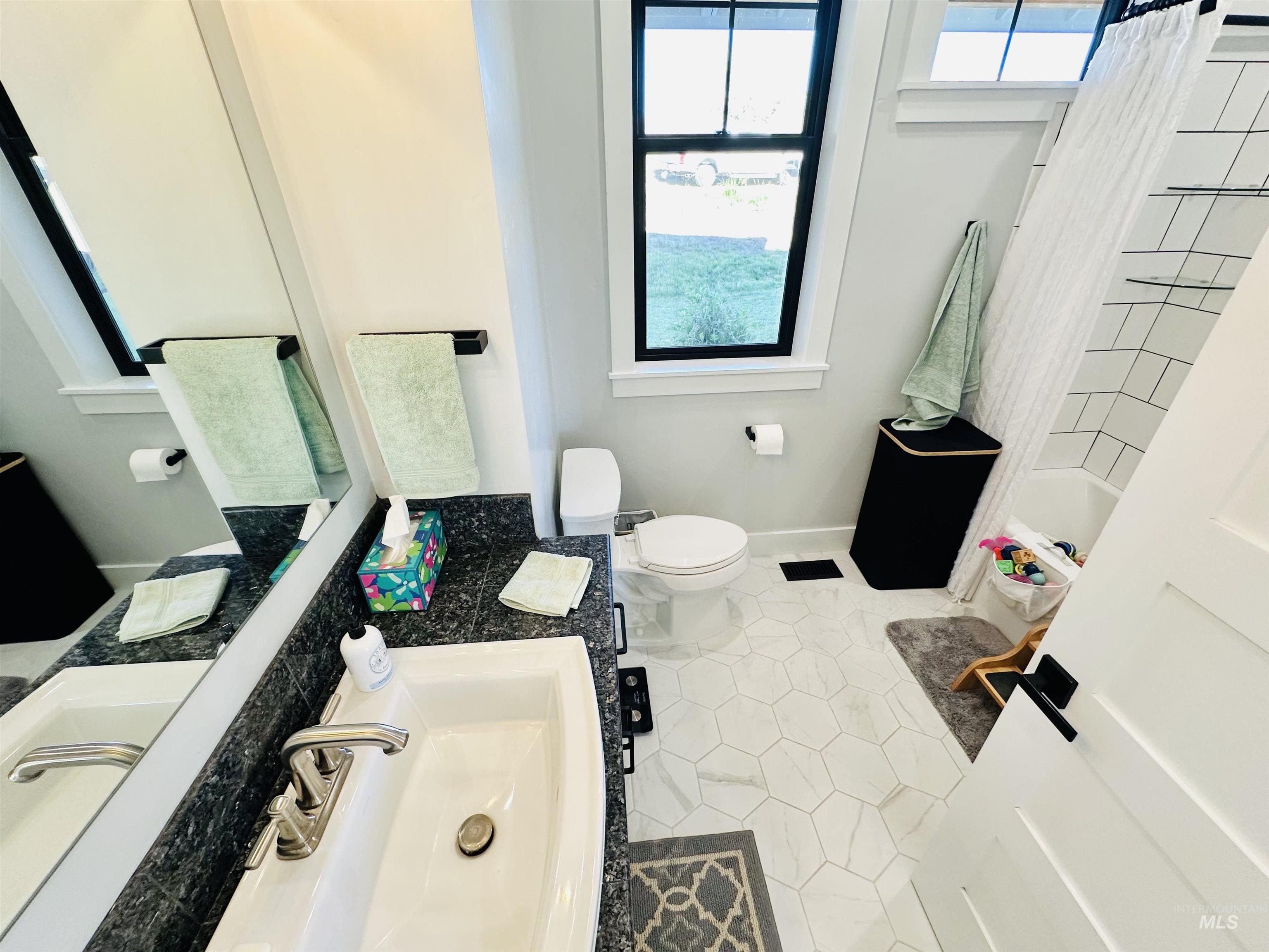 876 Coyote Gulch Road Adrian, OR 97901 - Photo 35 of 50 Bathroom featuring hexagonal floor tiling, a white vanity with an integrated sink, dark countertop, and a built-in bathtub with subway tile surround