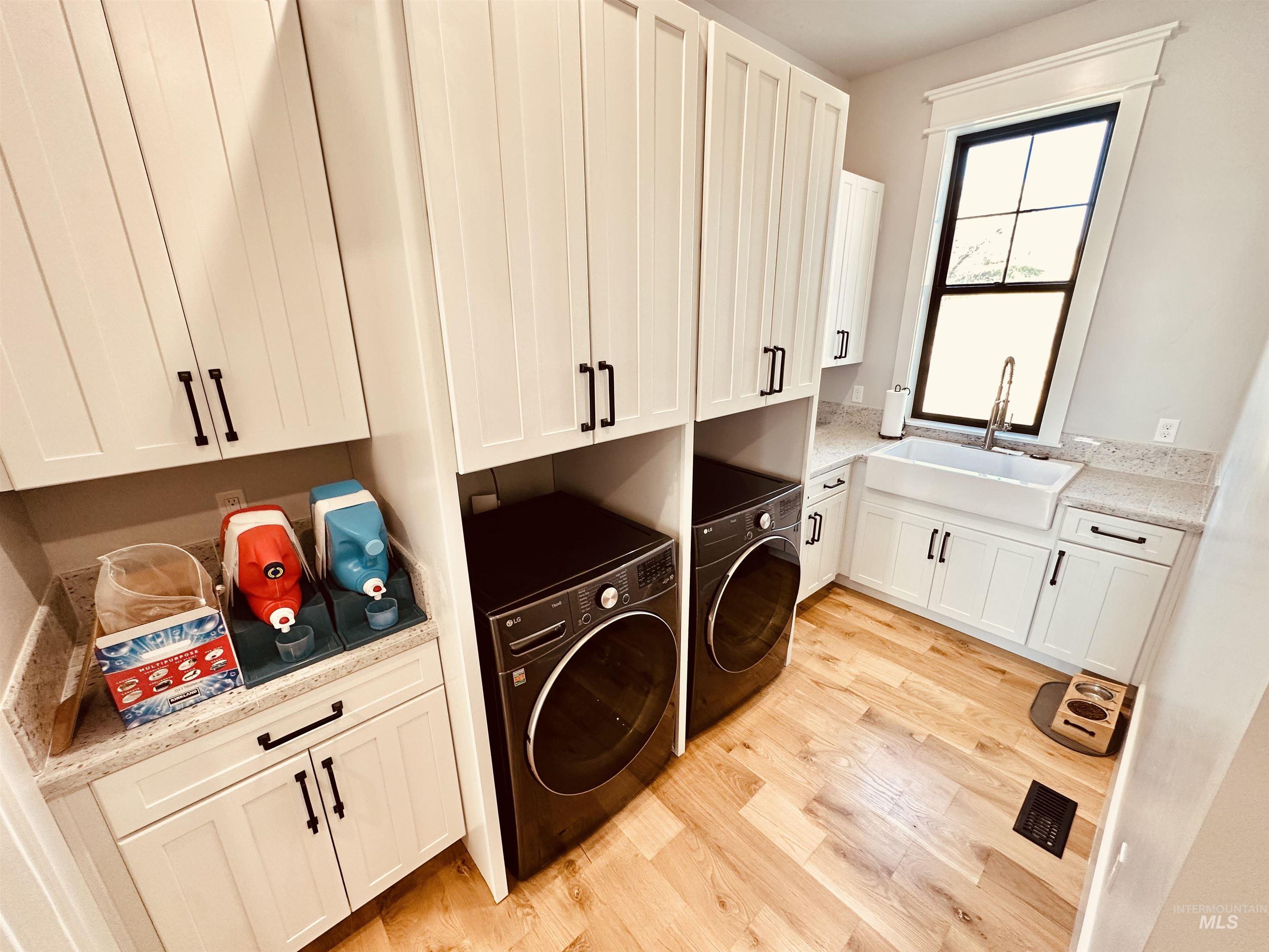 876 Coyote Gulch Road Adrian, OR 97901 - Photo 36 of 50 Laundry area featuring white shaker-style cabinetry, light wood-finish flooring, and a window with black trim
