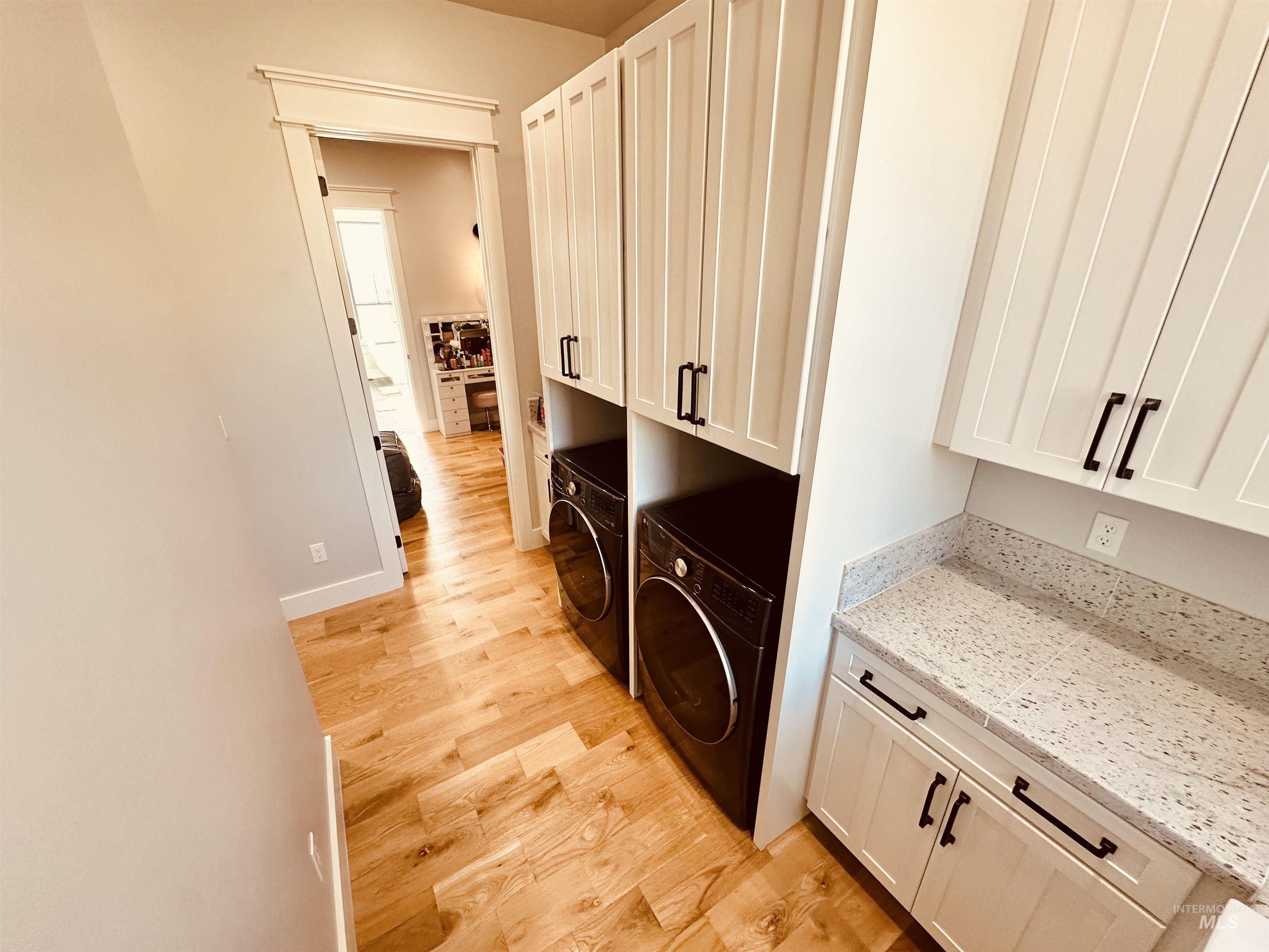 876 Coyote Gulch Road Adrian, OR 97901 - Photo 37 of 50 Dedicated laundry area featuring wood-finish flooring, white shaker-style cabinetry with matte black hardware, and a speckled countertop