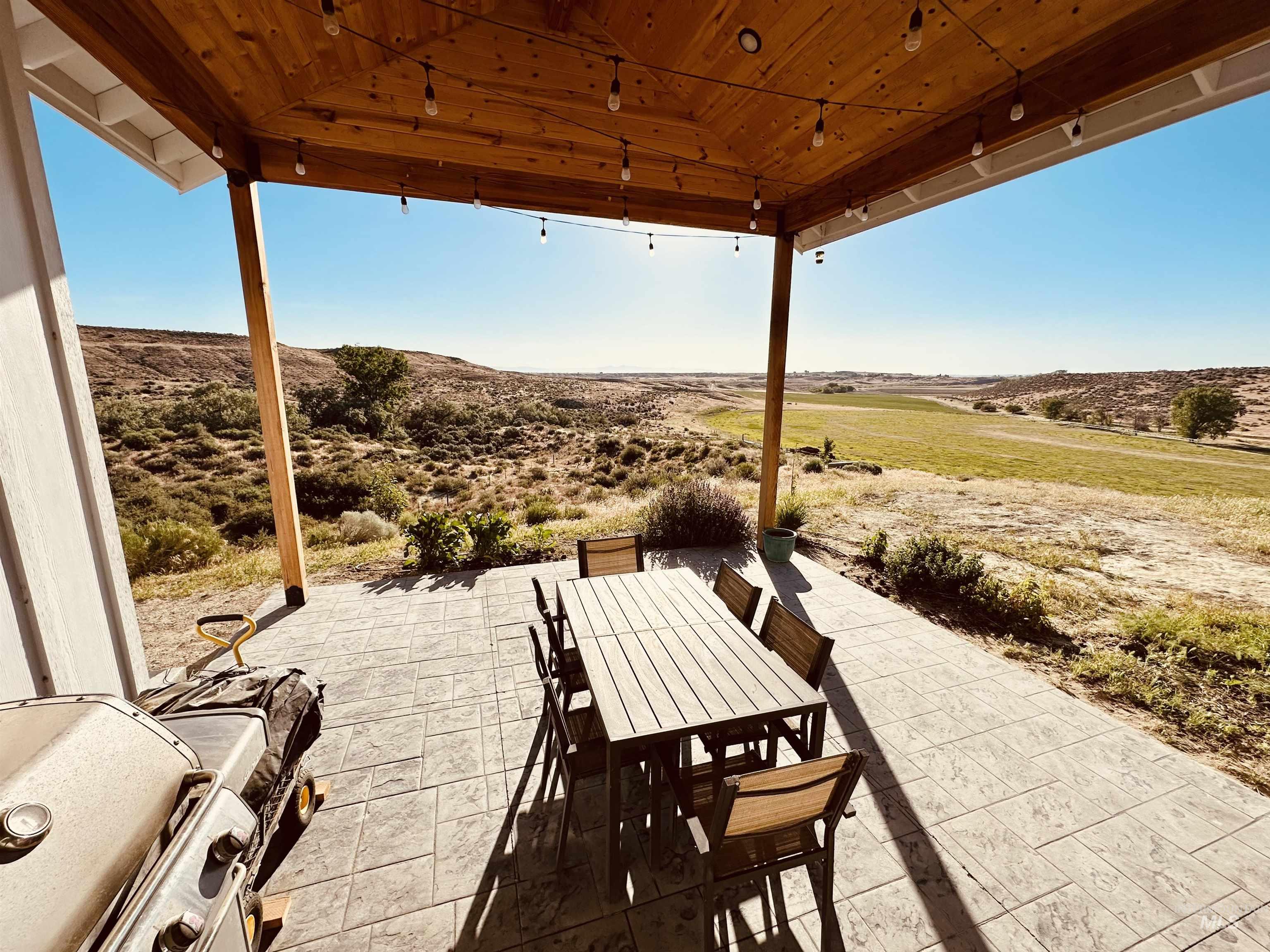 876 Coyote Gulch Road Adrian, OR 97901 - Photo 39 of 50 Expansive covered patio featuring a natural wood ceiling, string lighting, and stamped concrete flooring
