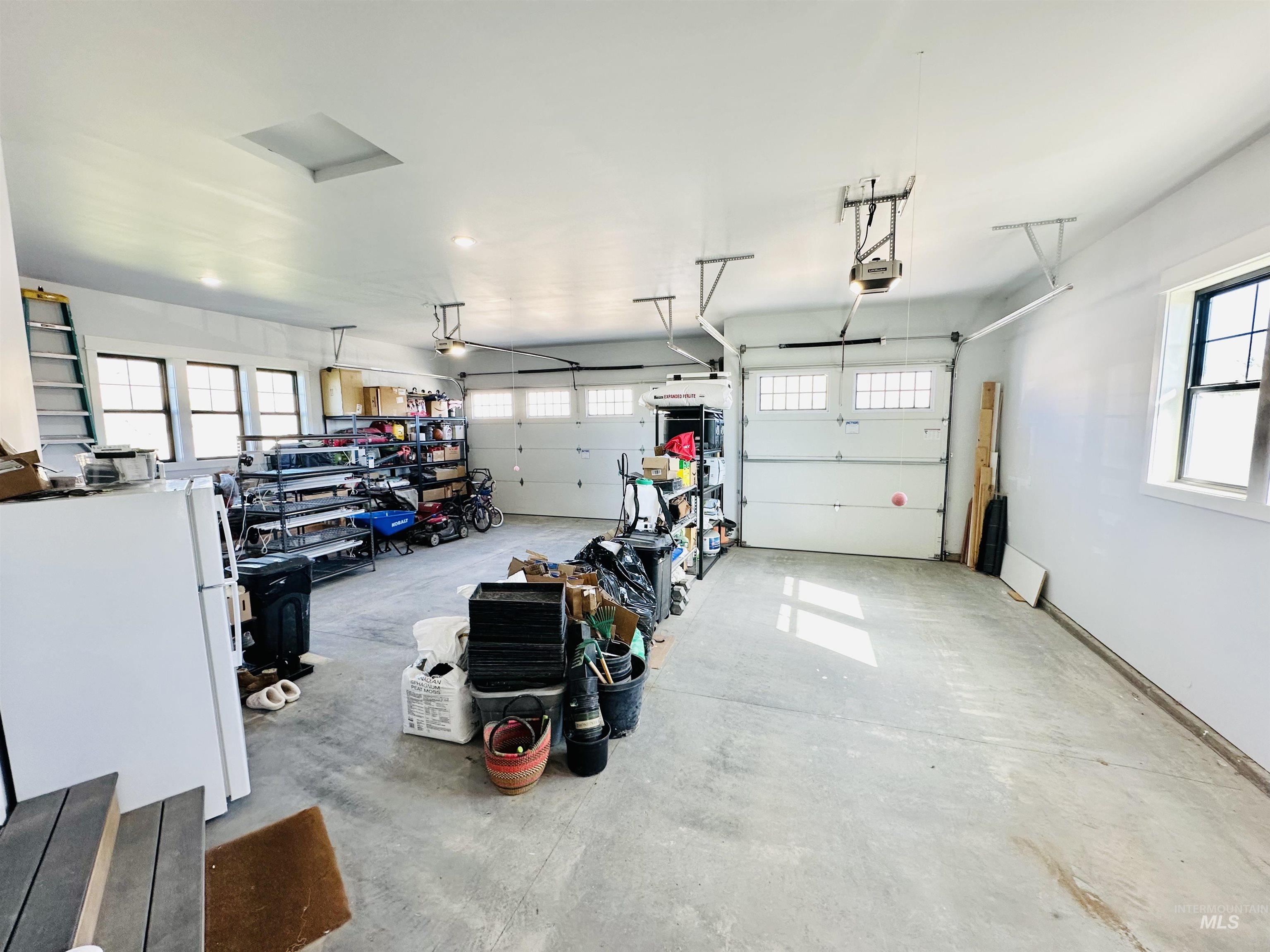876 Coyote Gulch Road Adrian, OR 97901 - Photo 45 of 50 Spacious garage featuring a concrete floor, multiple windows, two overhead garage doors with openers, and an overhead skylight