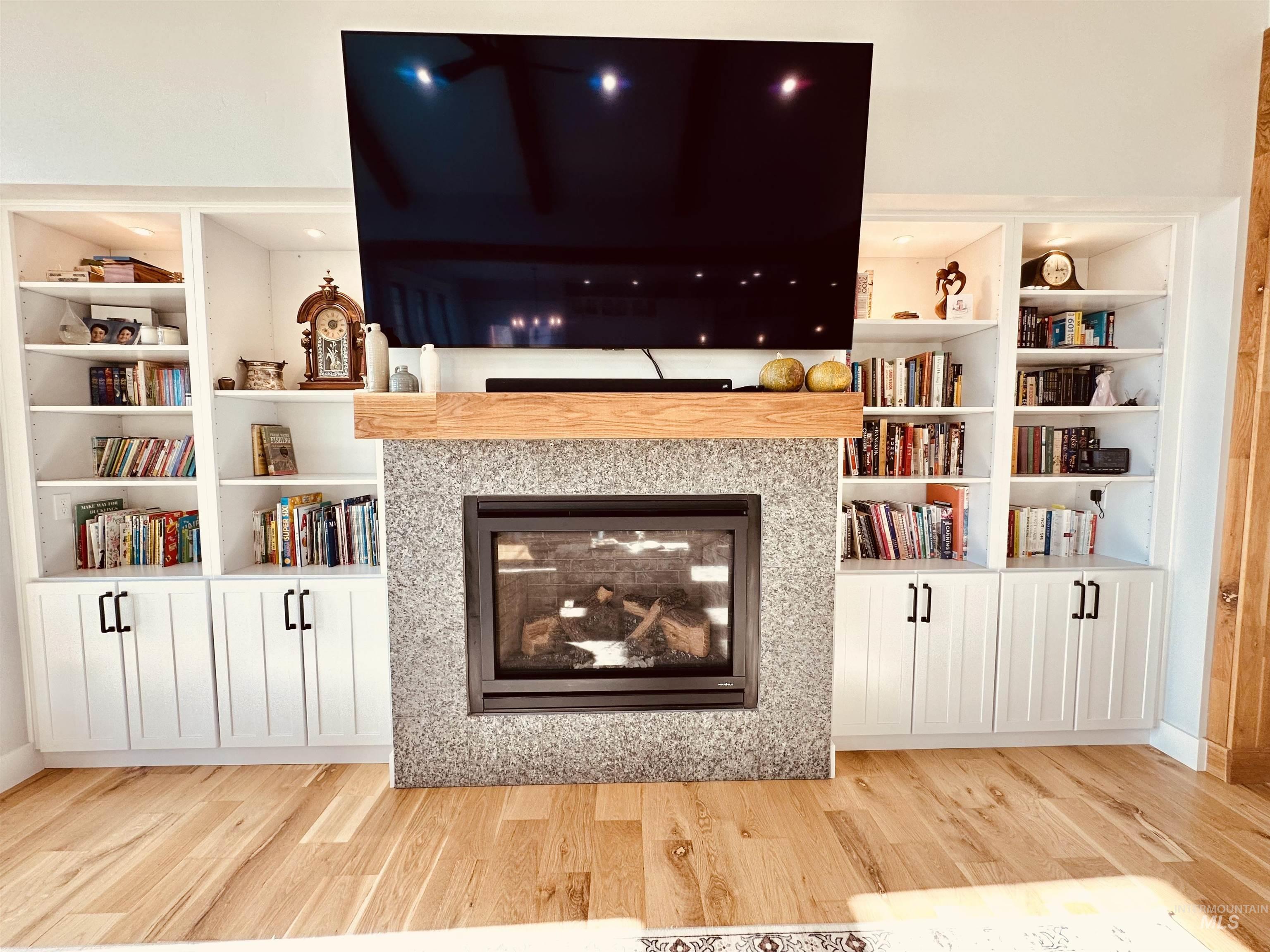 876 Coyote Gulch Road Adrian, OR 97901 - Photo 9 of 50 Built-in shelving and cabinetry flank a stone-surround fireplace with a natural wood mantel, all above wood-finish flooring