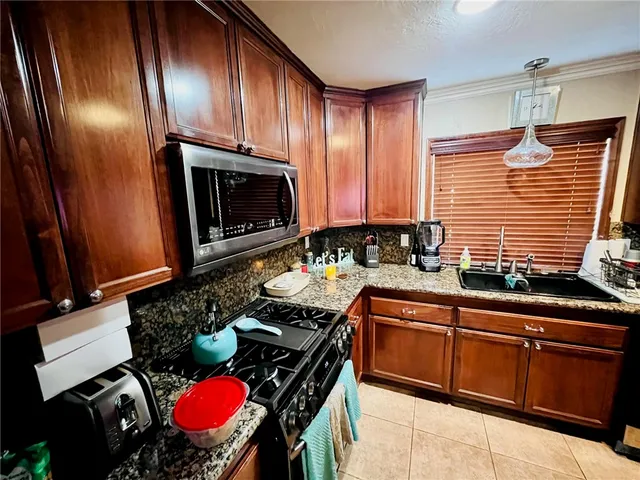 a kitchen with granite countertop a stove sink and microwave