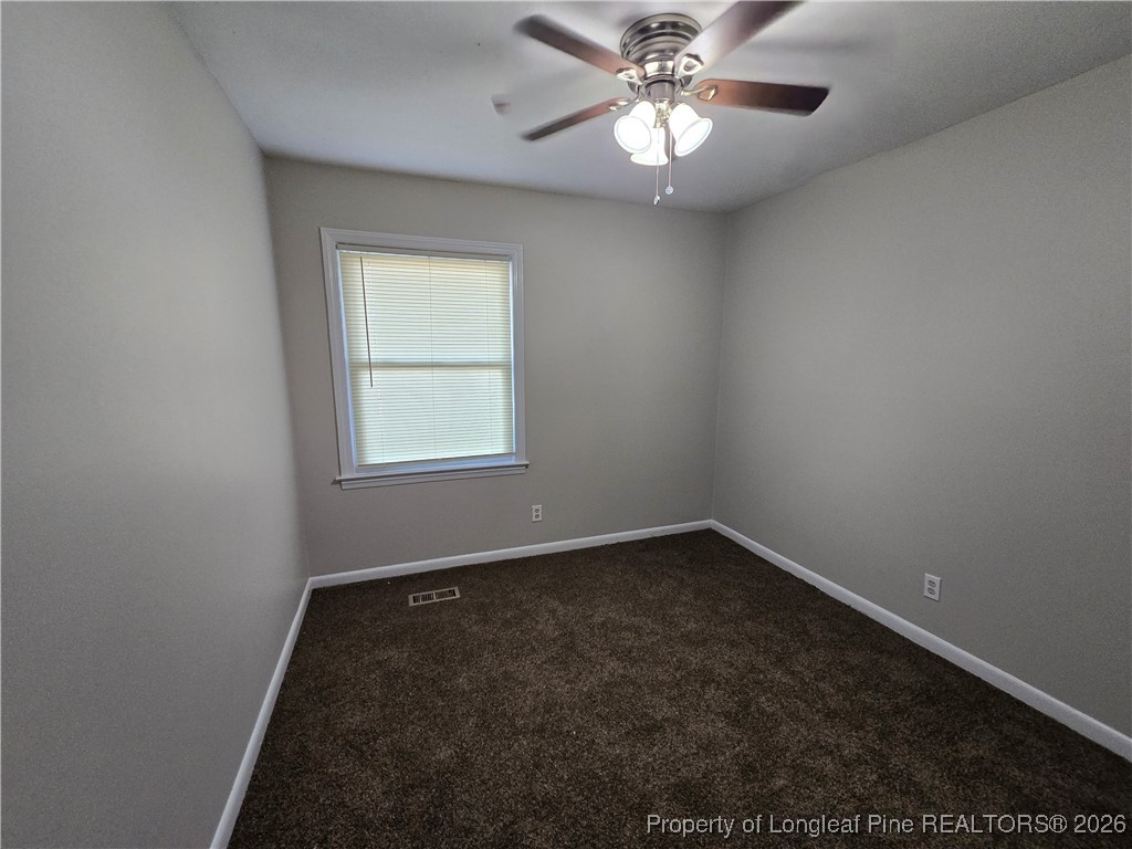 4617 Belford Road Fayetteville, NC 28314 - Photo 12 of 21 an empty room with a chandelier fan and windows