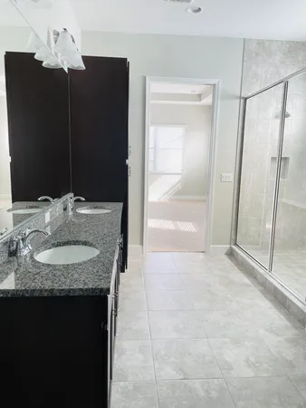 a bathroom with a granite countertop sink a mirror and shower