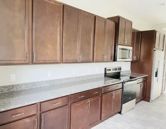 a kitchen with granite countertop wooden cabinets stainless steel appliances and a counter space