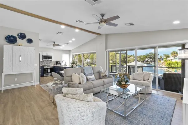a dining room with stainless steel appliances granite countertop furniture wooden floor and a chandelier