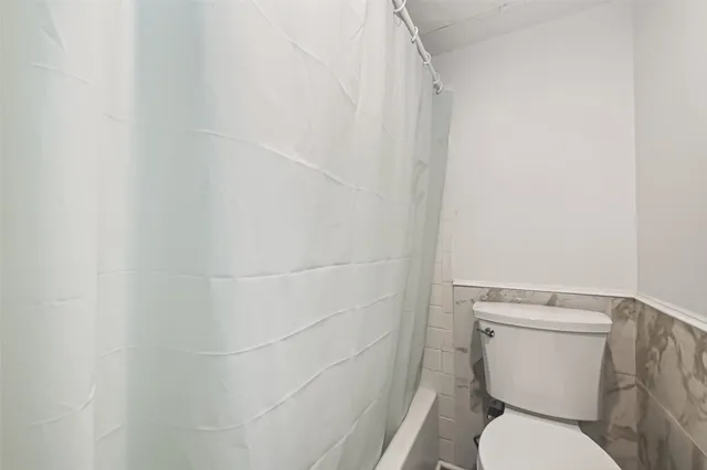 a white toilet sitting next to a shower