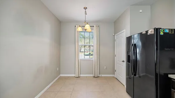 a view of an empty room with window and refrigerator