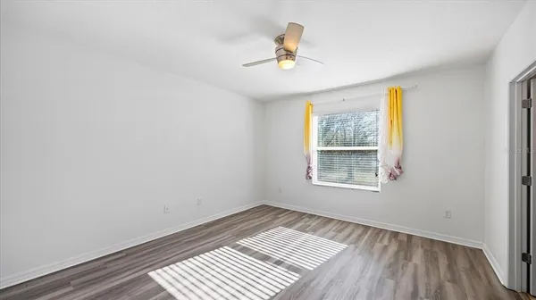 a view of an empty room with a window and wooden floor