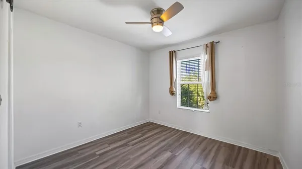 an empty room with a window and a ceiling fan