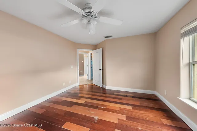 an empty room with a window and a ceiling fan