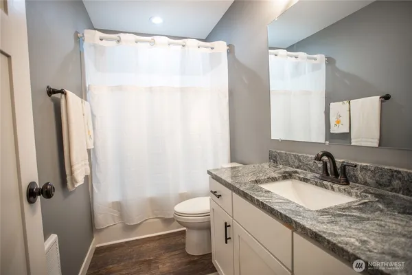 a bathroom with a granite countertop sink toilet and shower