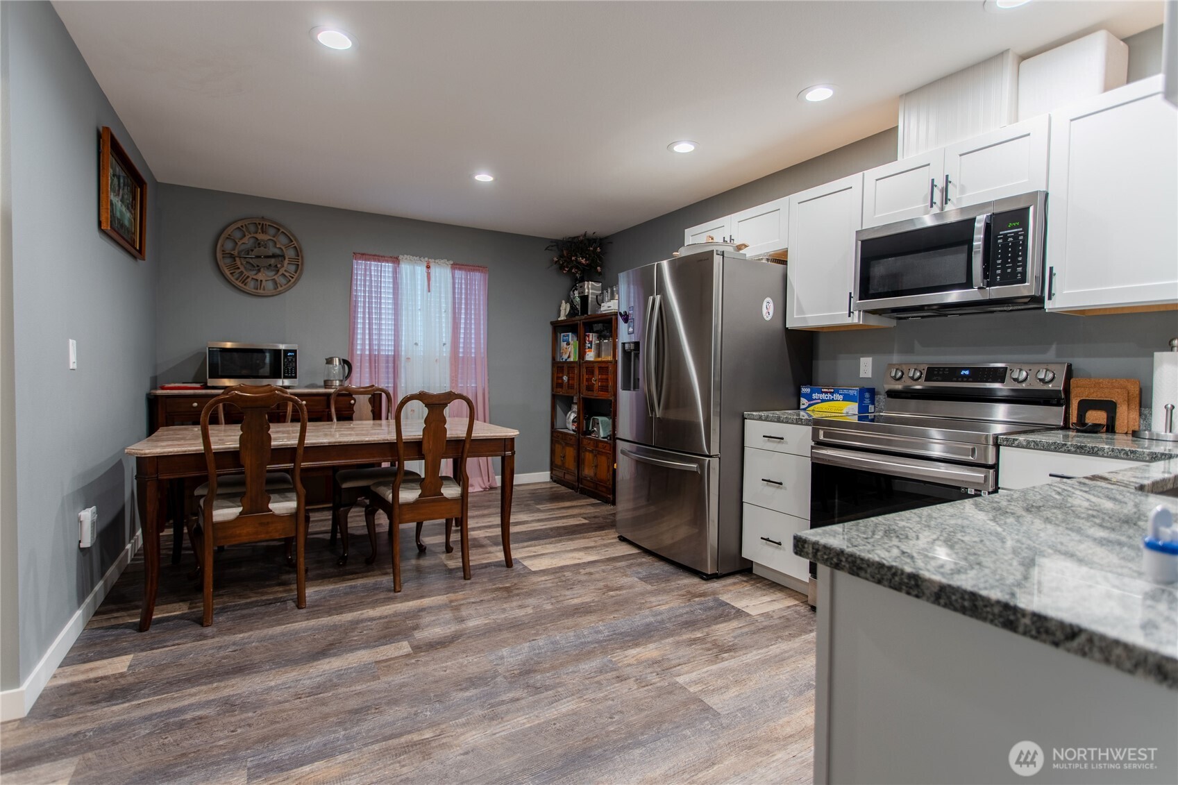 2915 Jackson Highway, Unit D Chehalis, WA 98532 - Photo 8 of 24 a kitchen with stainless steel appliances granite countertop a refrigerator a stove top oven a sink dishwasher a dining table and chairs with wooden floor