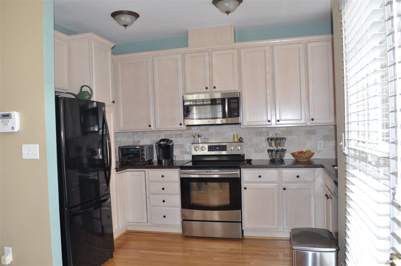 720 Parkham Lane Raleigh, NC 27603 - Photo 3 of 23 a kitchen with granite countertop a refrigerator stove and white cabinets