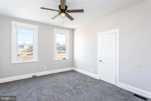 an empty room with windows and fan