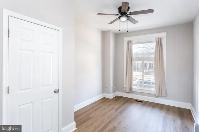 an empty room with wooden floor ceiling fan and windows