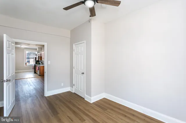 a view of a hallway with wooden floor and a bathroom