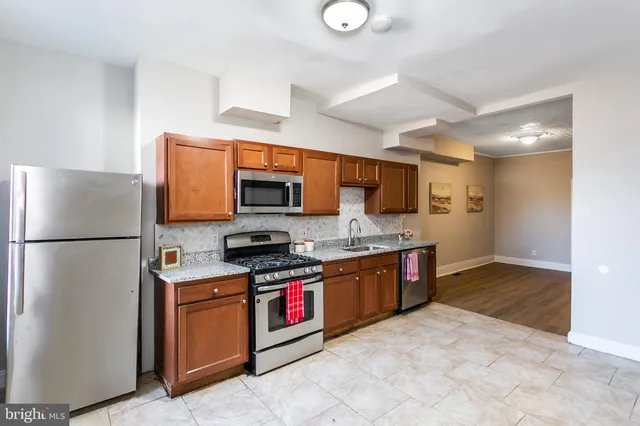 a kitchen with stainless steel appliances granite countertop a refrigerator a stove top oven a sink and dishwasher