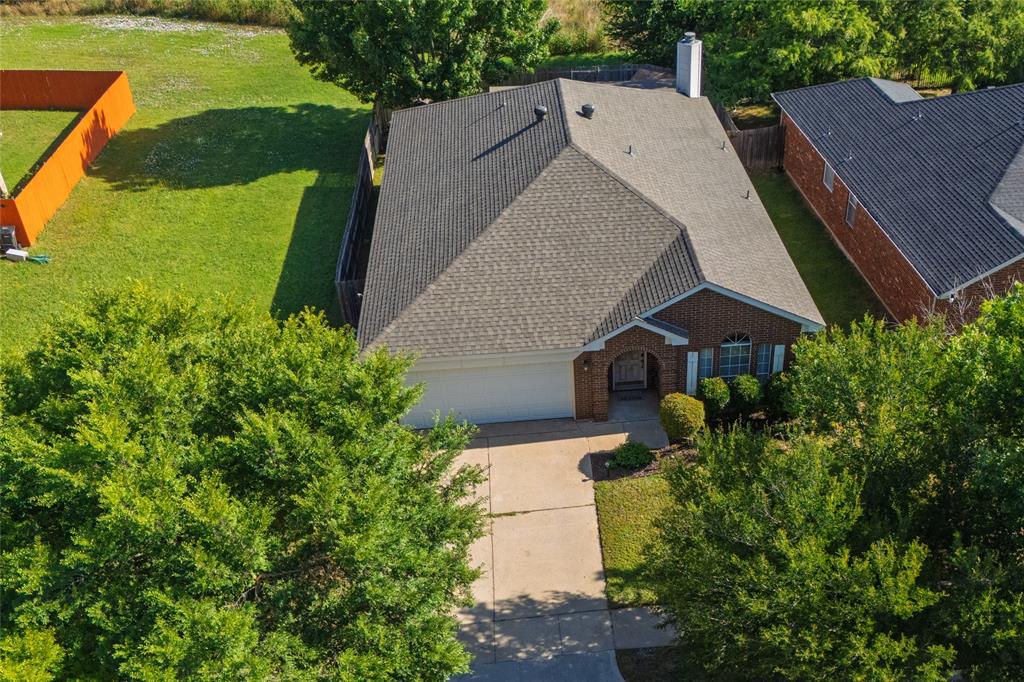 4025 Chisos Rim Trail Fort Worth, TX 76244 - Photo 39 of 40 Traditional brick exterior with an attached garage, a mature tree-lined driveway, and a gabled roof