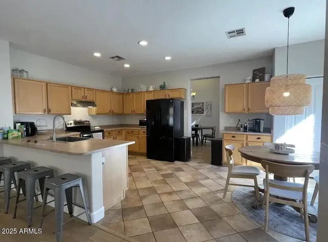 a kitchen with stainless steel appliances granite countertop a refrigerator a stove a sink a dining table and chairs