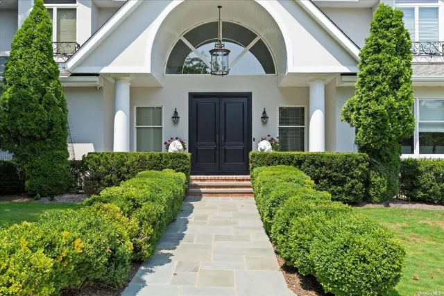 a view of a house with a large windows and flower plants