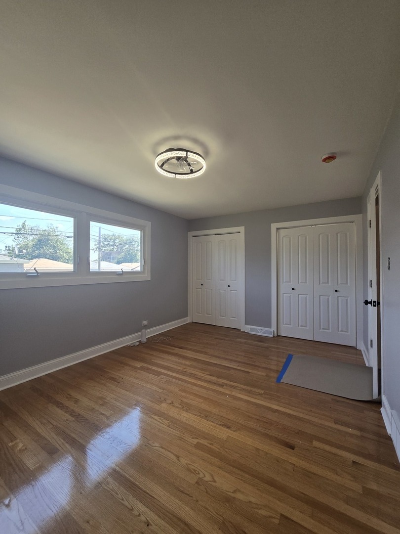 9727 South Michigan Avenue Chicago, IL 60628 - Photo 13 of 24 a view of an empty room with wooden floor and a window