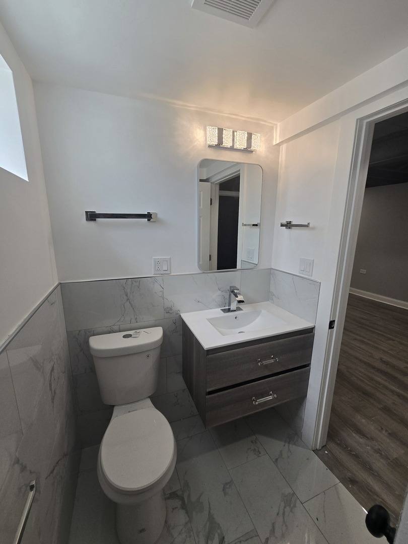 9727 South Michigan Avenue Chicago, IL 60628 - Photo 17 of 24 a bathroom with a toilet sink and mirror