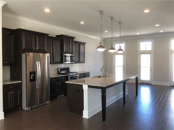 a kitchen with stainless steel appliances granite countertop a refrigerator a sink dishwasher a stove and a refrigerator with wooden floor