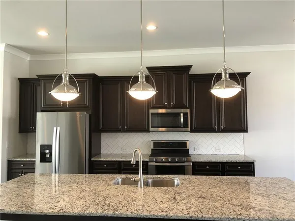 a kitchen with stainless steel appliances granite countertop a stove a refrigerator and a wooden cabinets