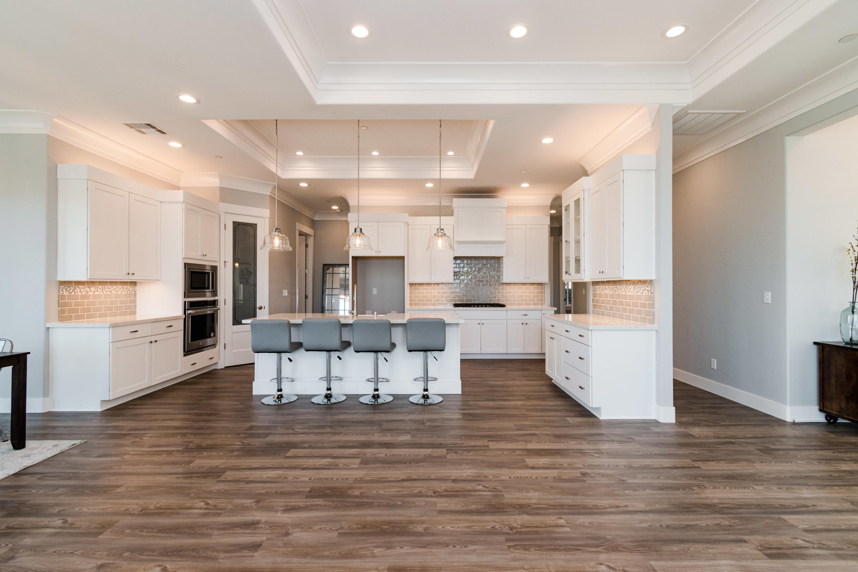 808 River Bend Road Redding, CA 96003 - Photo 14 of 43 a large white kitchen with stainless steel appliances kitchen island granite countertop a large refrigerator a stove and white cabinets with wooden floor