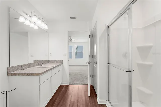 a bathroom with a granite countertop sink a mirror and shower