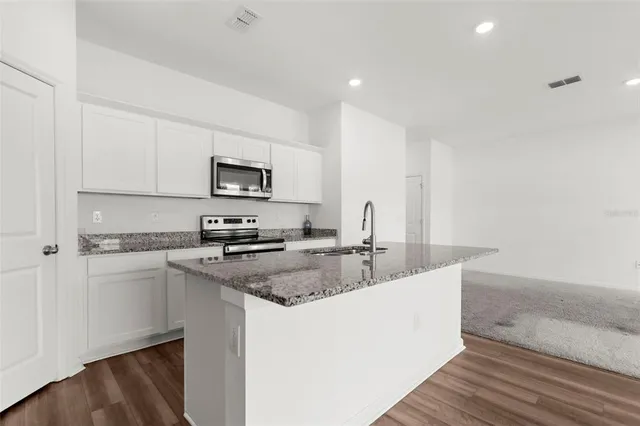 a kitchen with stainless steel appliances granite countertop a sink stove and microwave