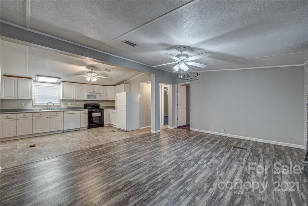 1349 Sherwood Road Clover, SC 29710 - Photo 6 of 23 a view of an empty room with a kitchen counter space wooden floor and a ceiling fan